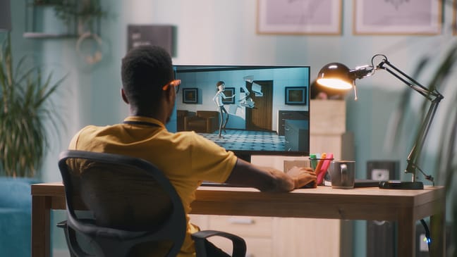 Black man in glasses rendering 3D cartoon on computer while working in home office
