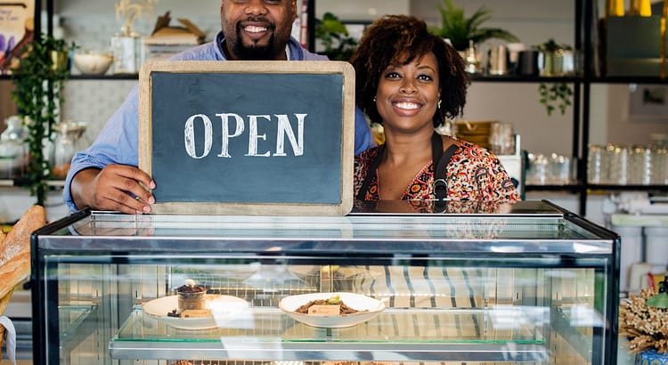 Cake cafe owners with open sign