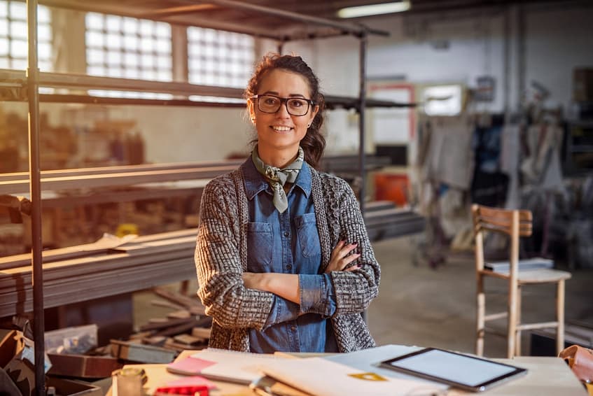 Strong confident middle aged woman engineer standing and looking at the camera at her workshop.