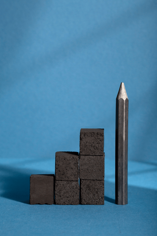 An image of black blocks stacked up beside a black pencil depicting creative block